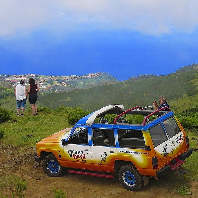 Tourists admiring the coastal view beside a parked Green Devil 4x4 jeep, Madeira.