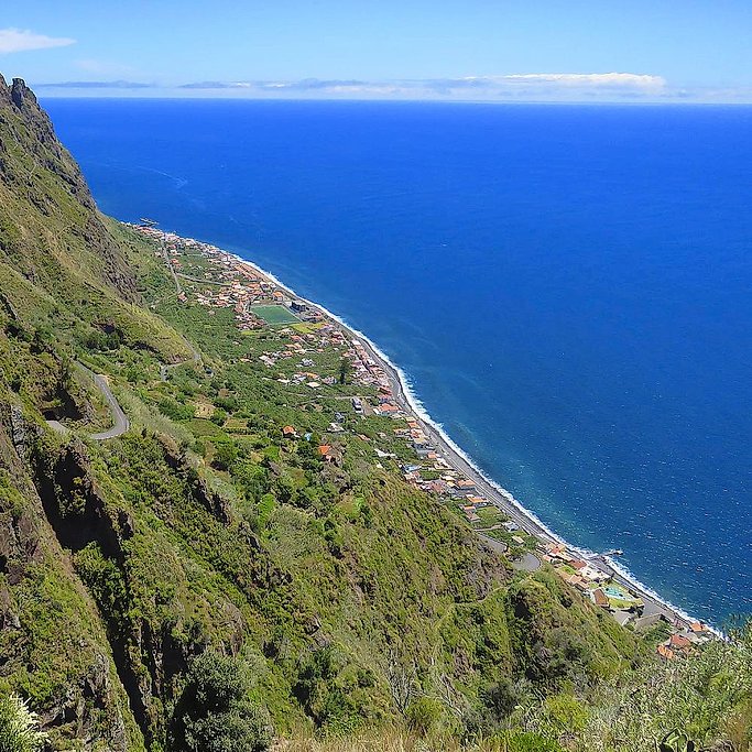 Aerial view along Madeira's southwest coast, a village squeezed between steep cliffs and the sea.